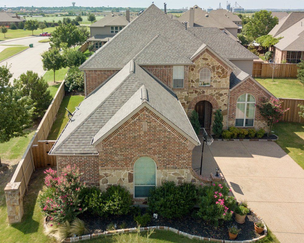 an aerial view of a brick house with a gray roof