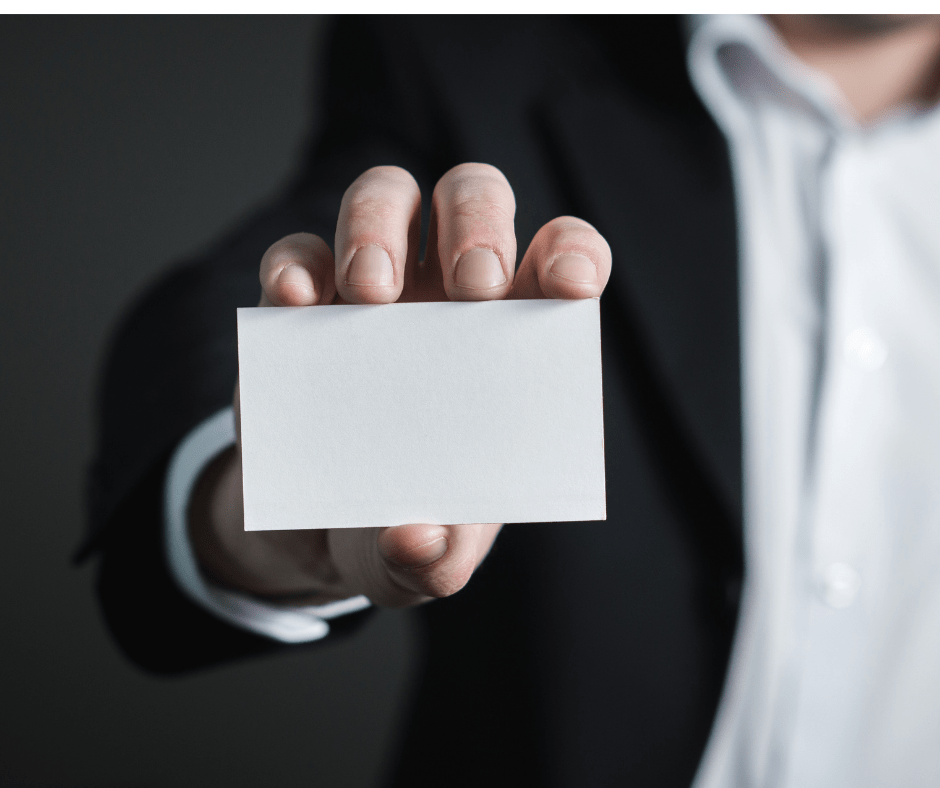 Man in suit holding a blank business card forward.