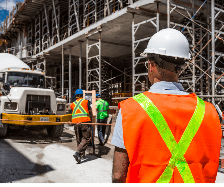 Construction worker in hard hat and orange vest overseeing a building site. Construction worker in hard hat and orange vest overseeing a building site.