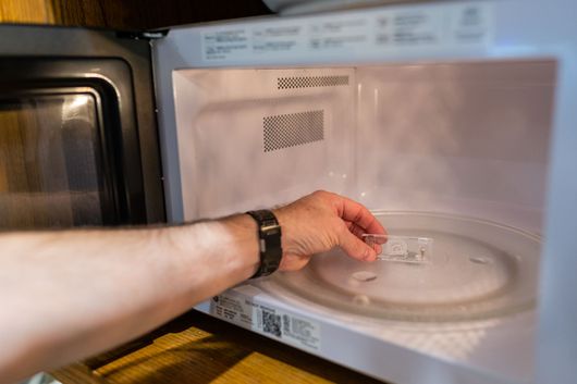 Hand placing a glass plate into a microwave oven