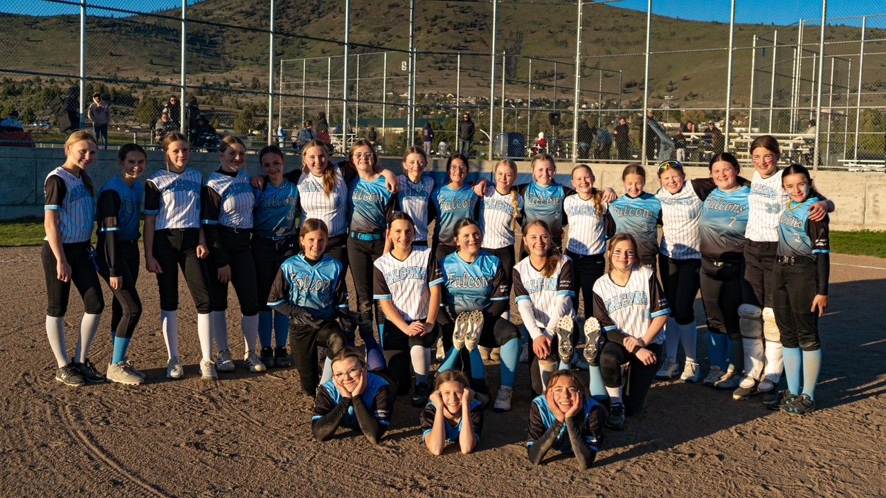 Youth soccer team posing on a field, wearing blue and white uniforms, with mountains in the background