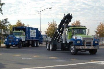 Two garbage trucks are parked on the side of the road.