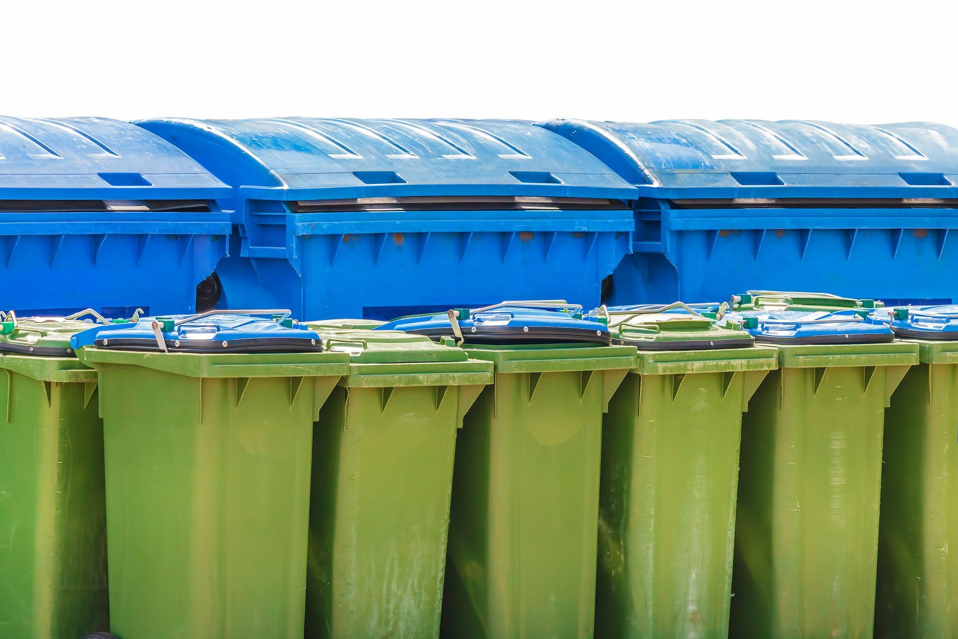 A row of green and blue trash cans are lined up in a row.