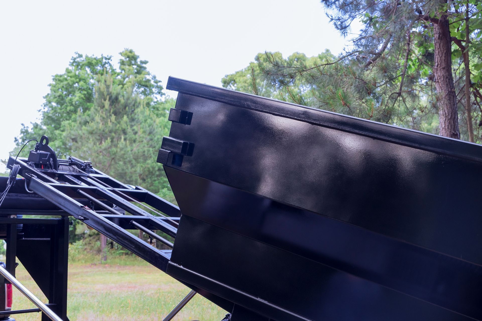 A dumpster is sitting on top of a trailer in a field.