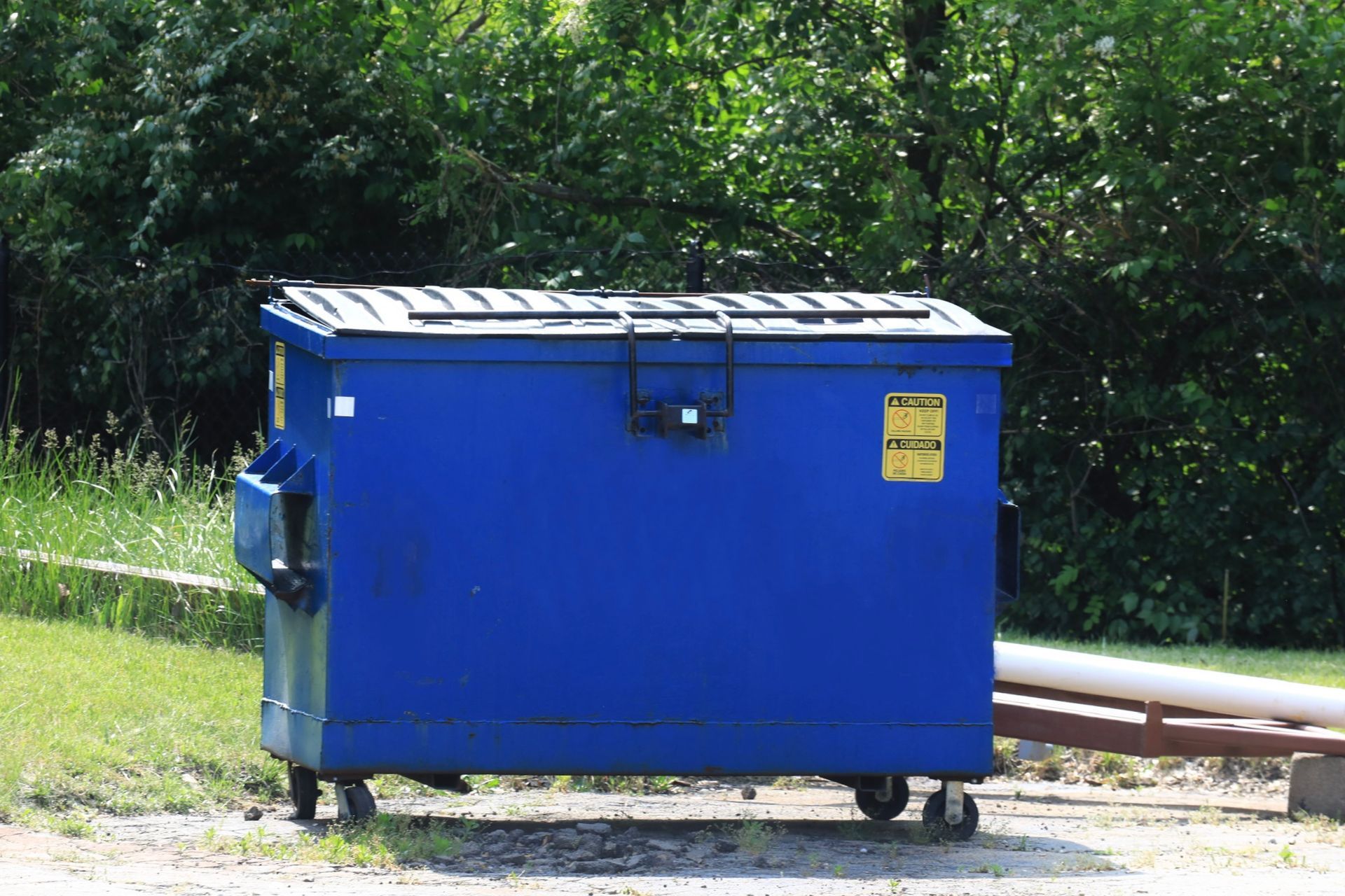 A blue dumpster with a yellow warning sign on it