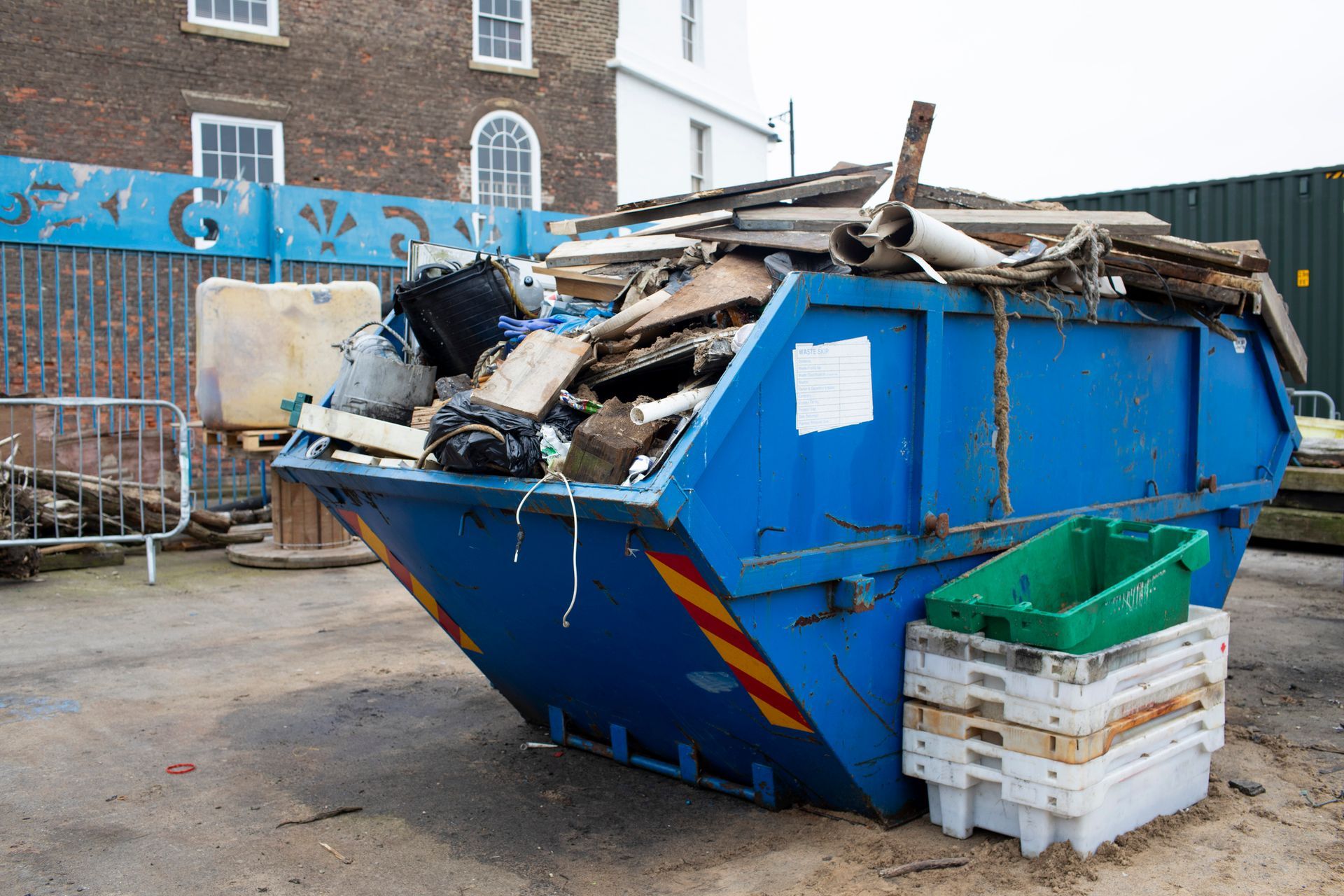 A blue dumpster is filled with a lot of garbage