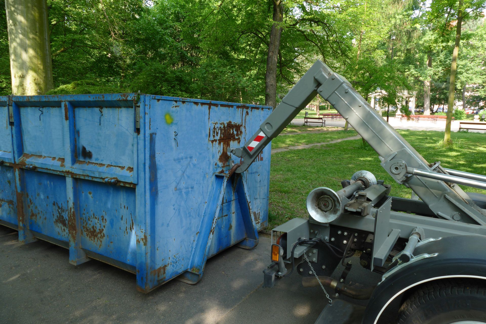 A blue dumpster is being towed by a truck