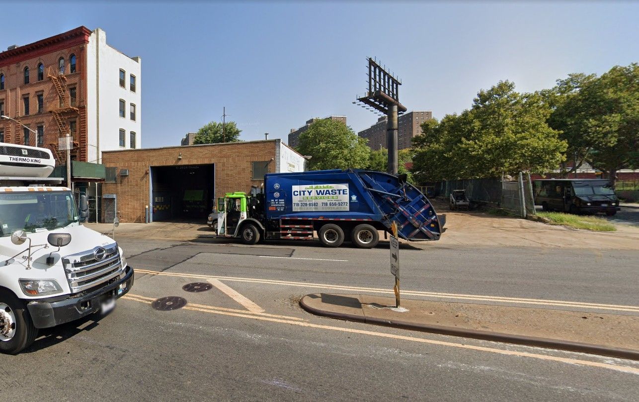 A blue dumpster is parked on the side of the road
