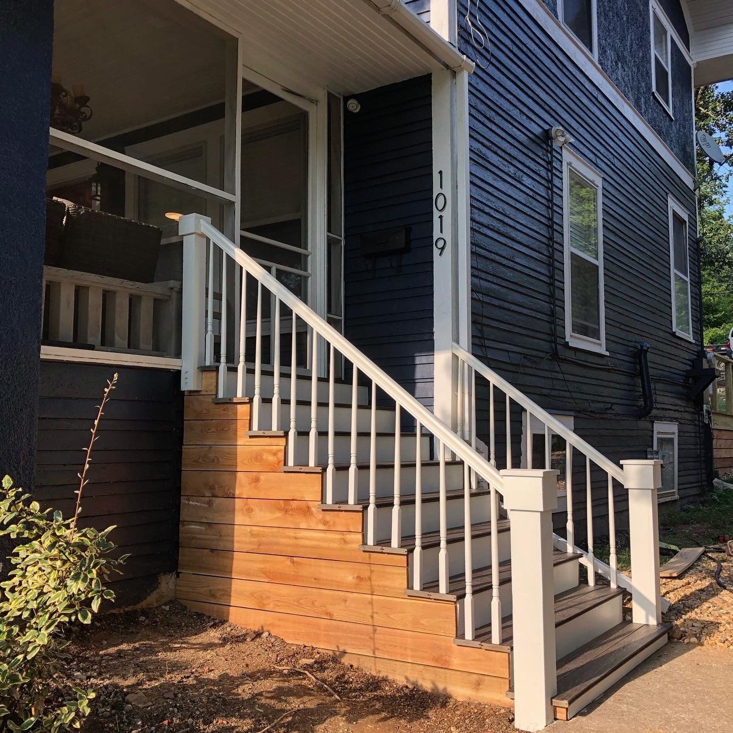 A blue house with a white railing and stairs