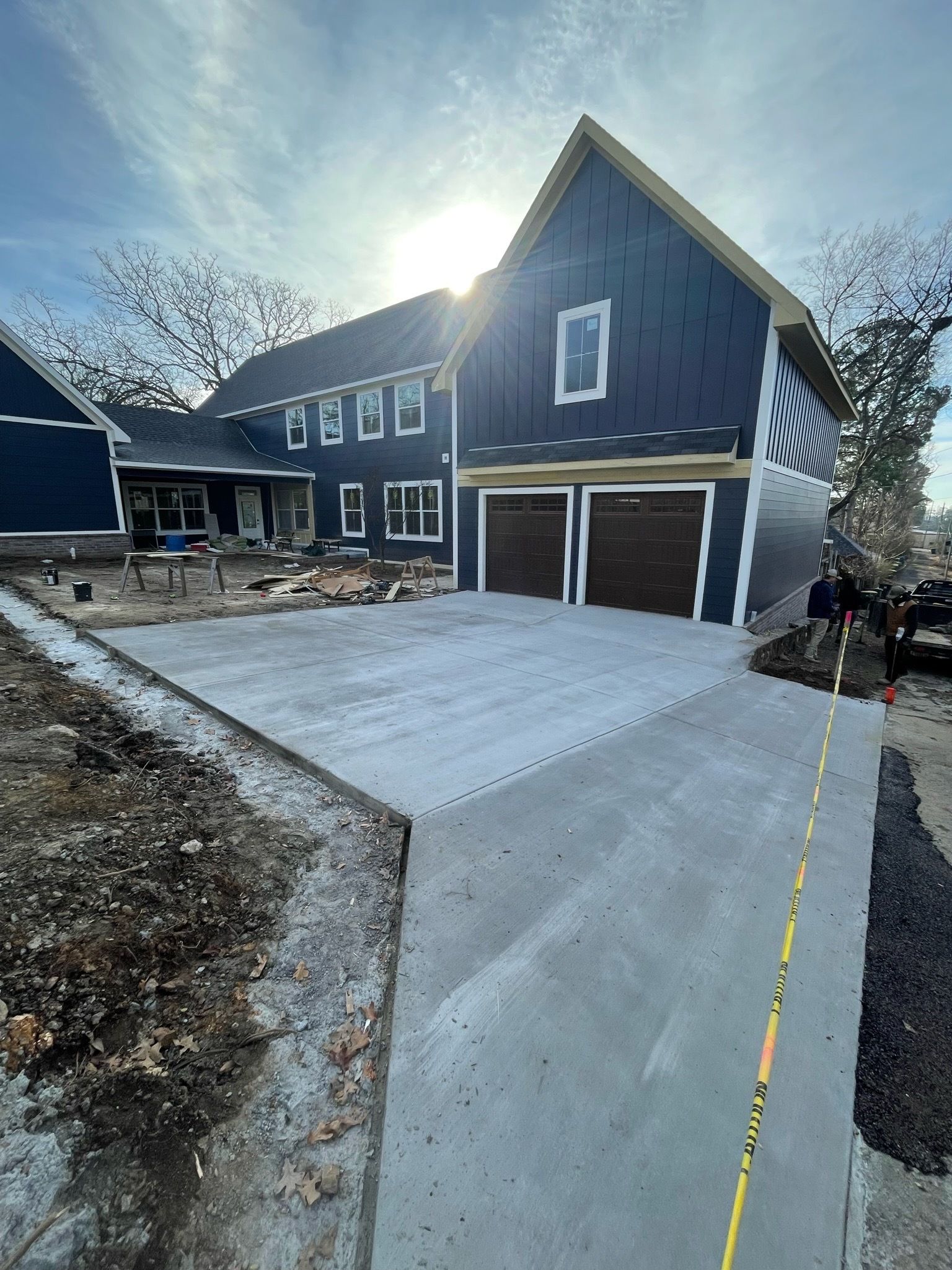A blue house is being built with a concrete driveway in front of it.