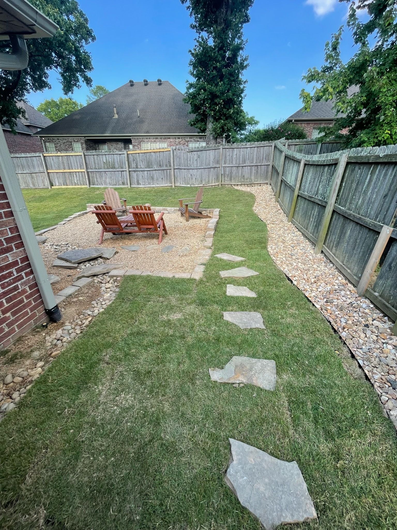 A backyard with a stone walkway leading to a fire pit.