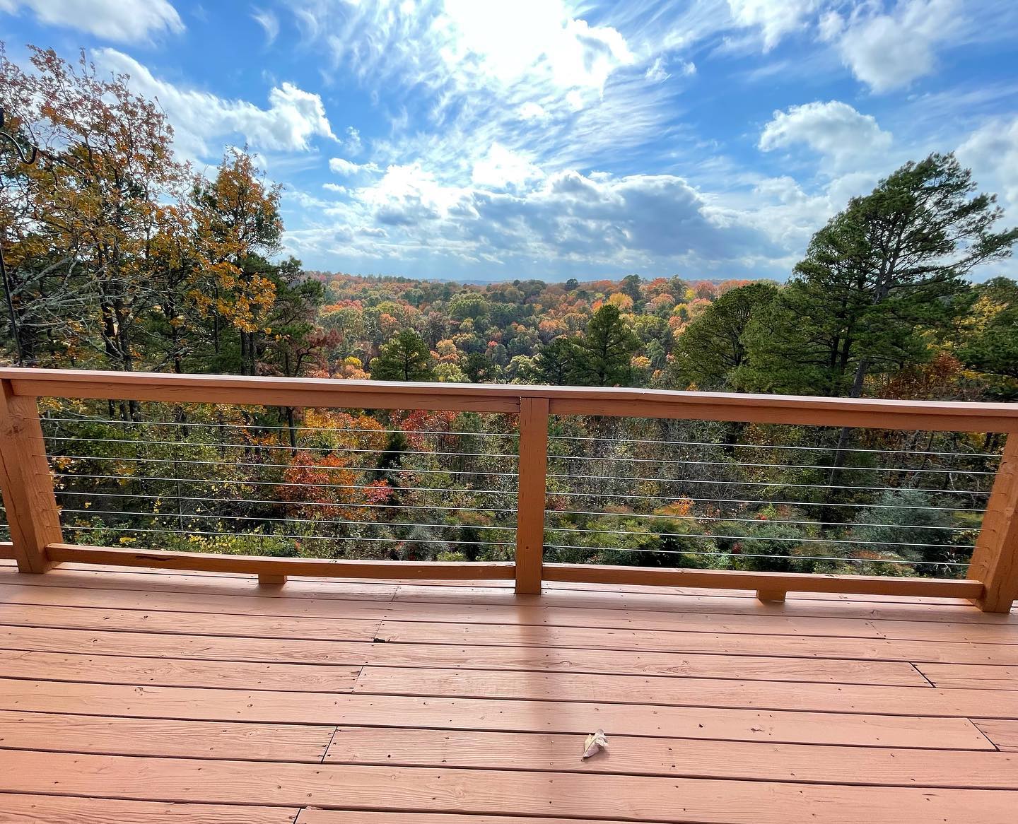 A wooden deck with a view of a forest on a sunny day.