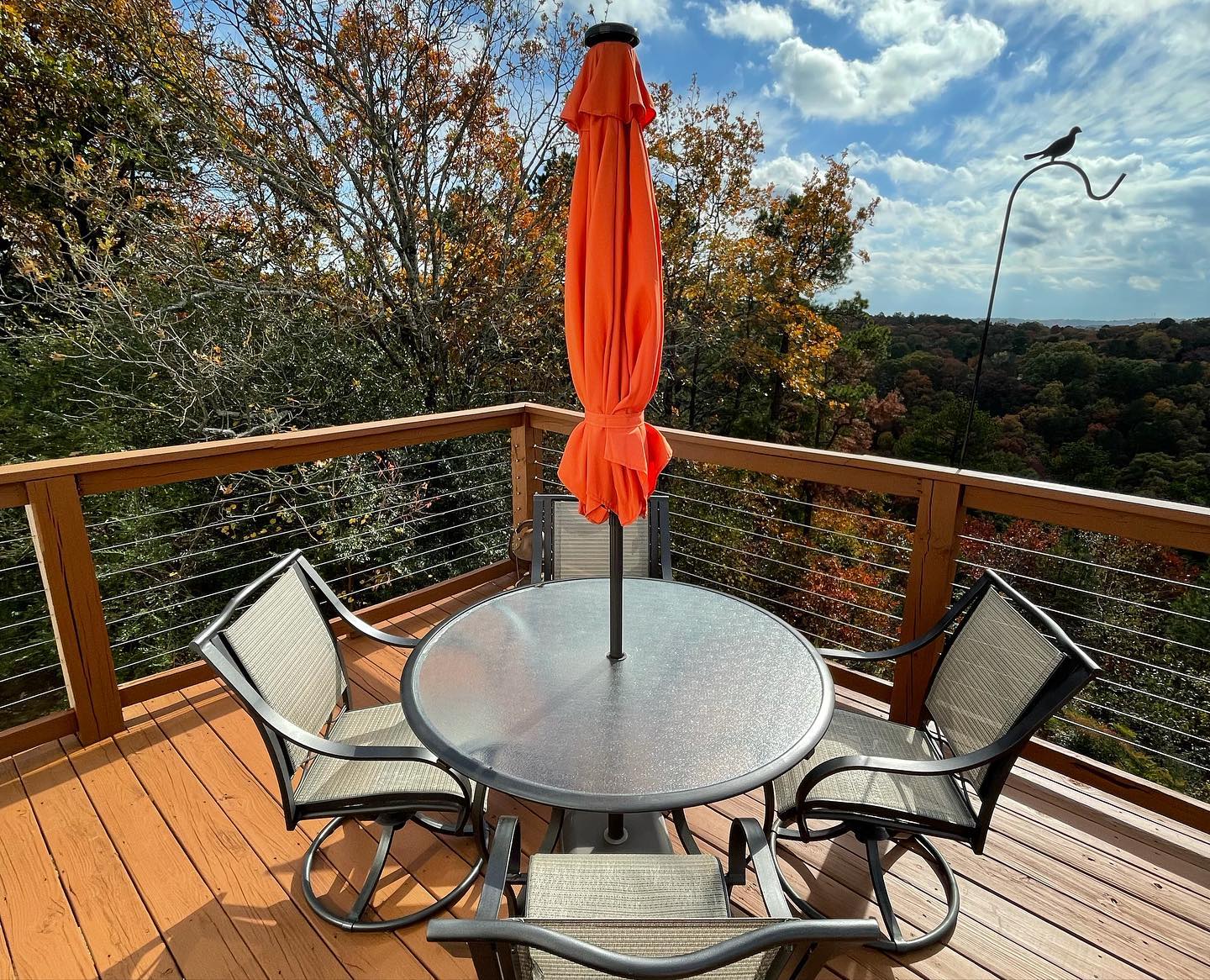 A deck with a table and chairs and an orange umbrella