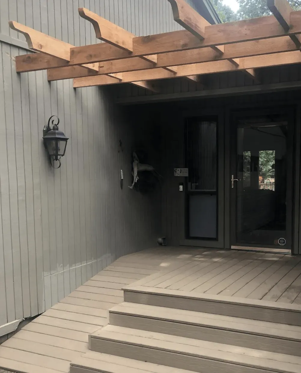 A wooden deck with stairs and a pergola over it