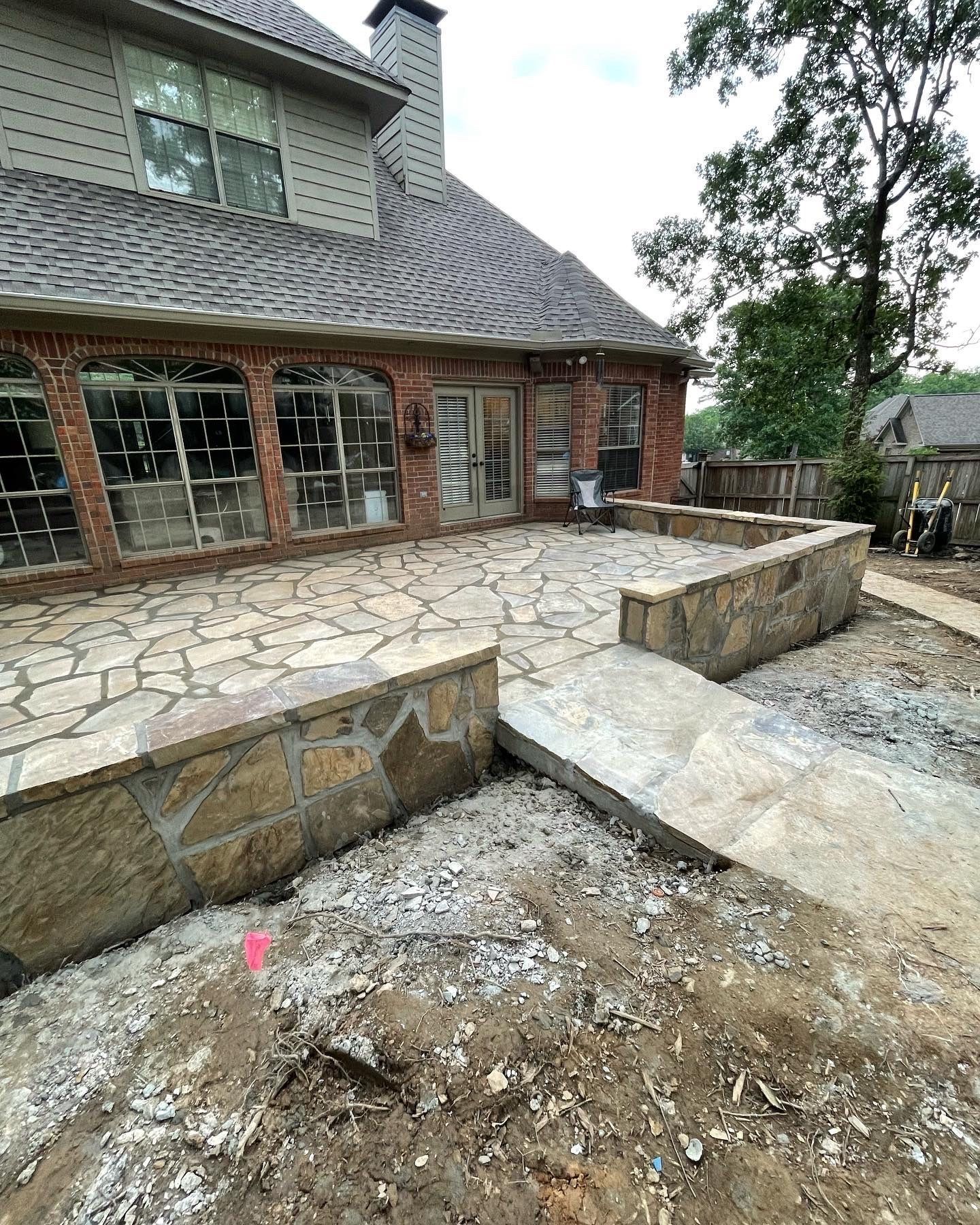 A large brick house with a stone patio in front of it.