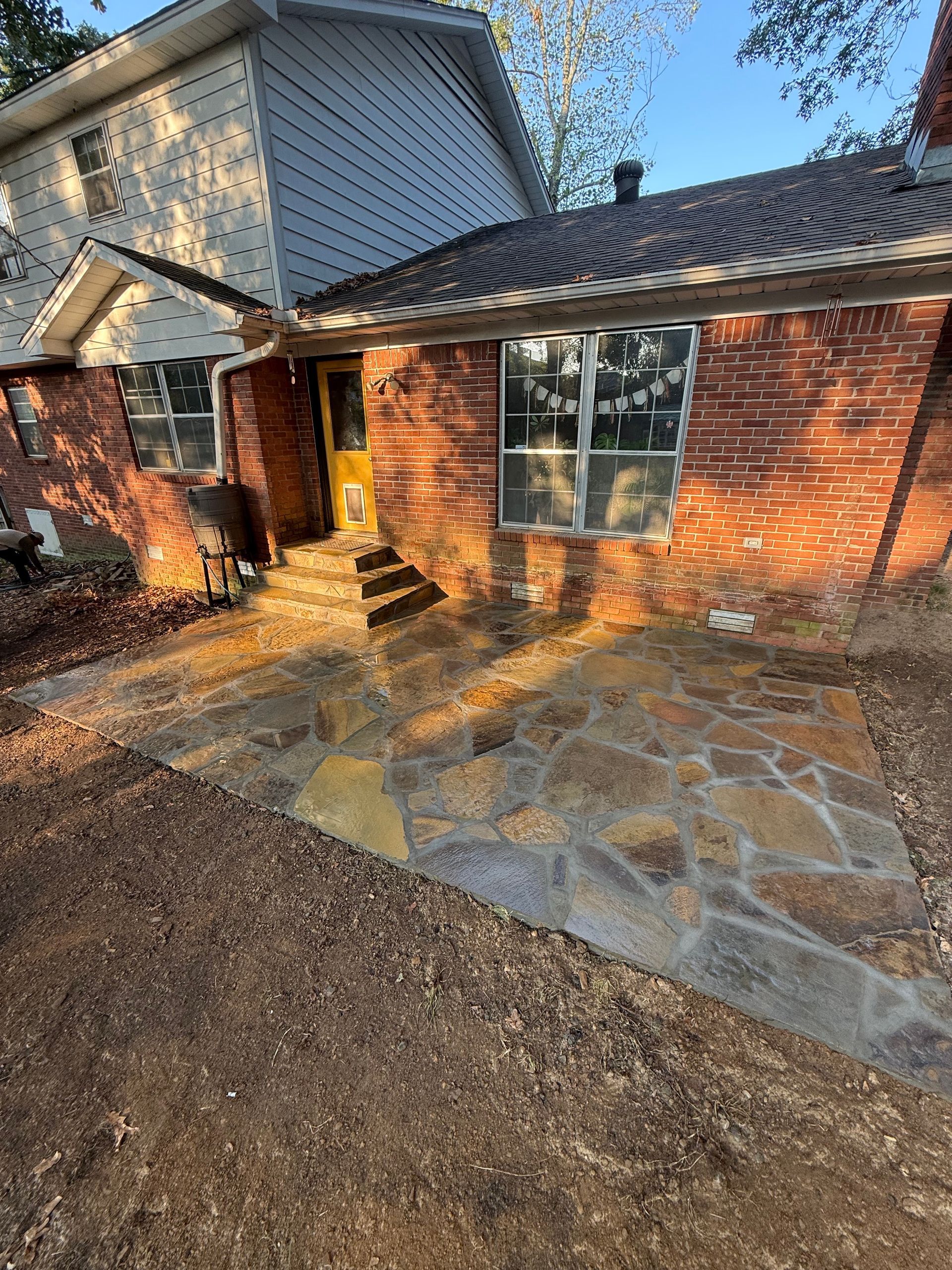 Brick house with flagstone patio, steps up to door, windows.