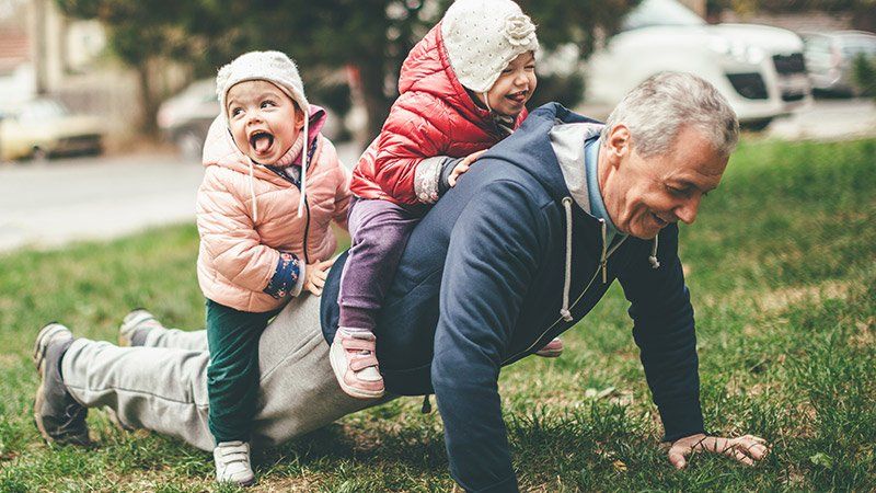 older man holds young children on his back