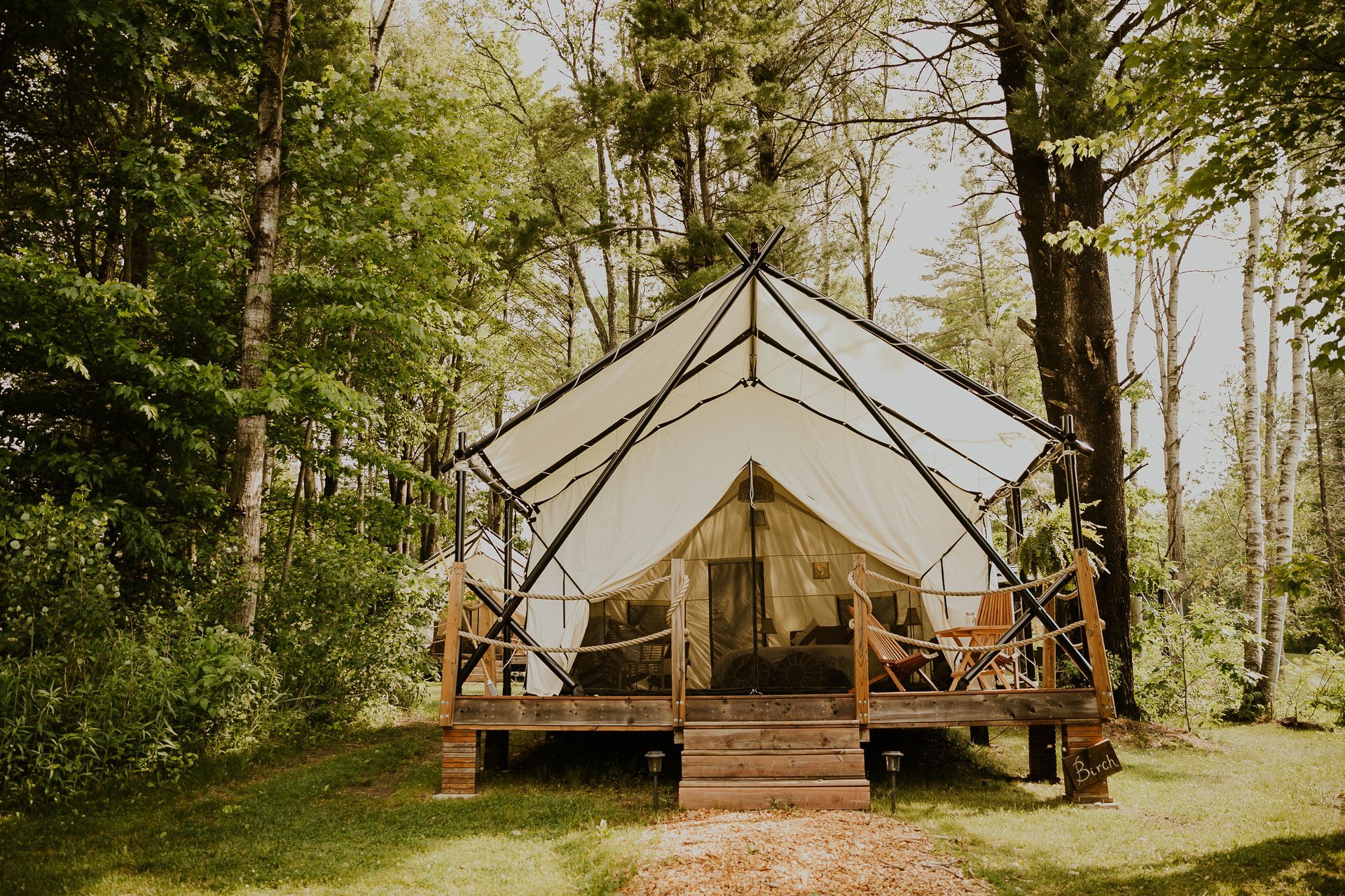 Canvas tent on a wooden deck in a forest.