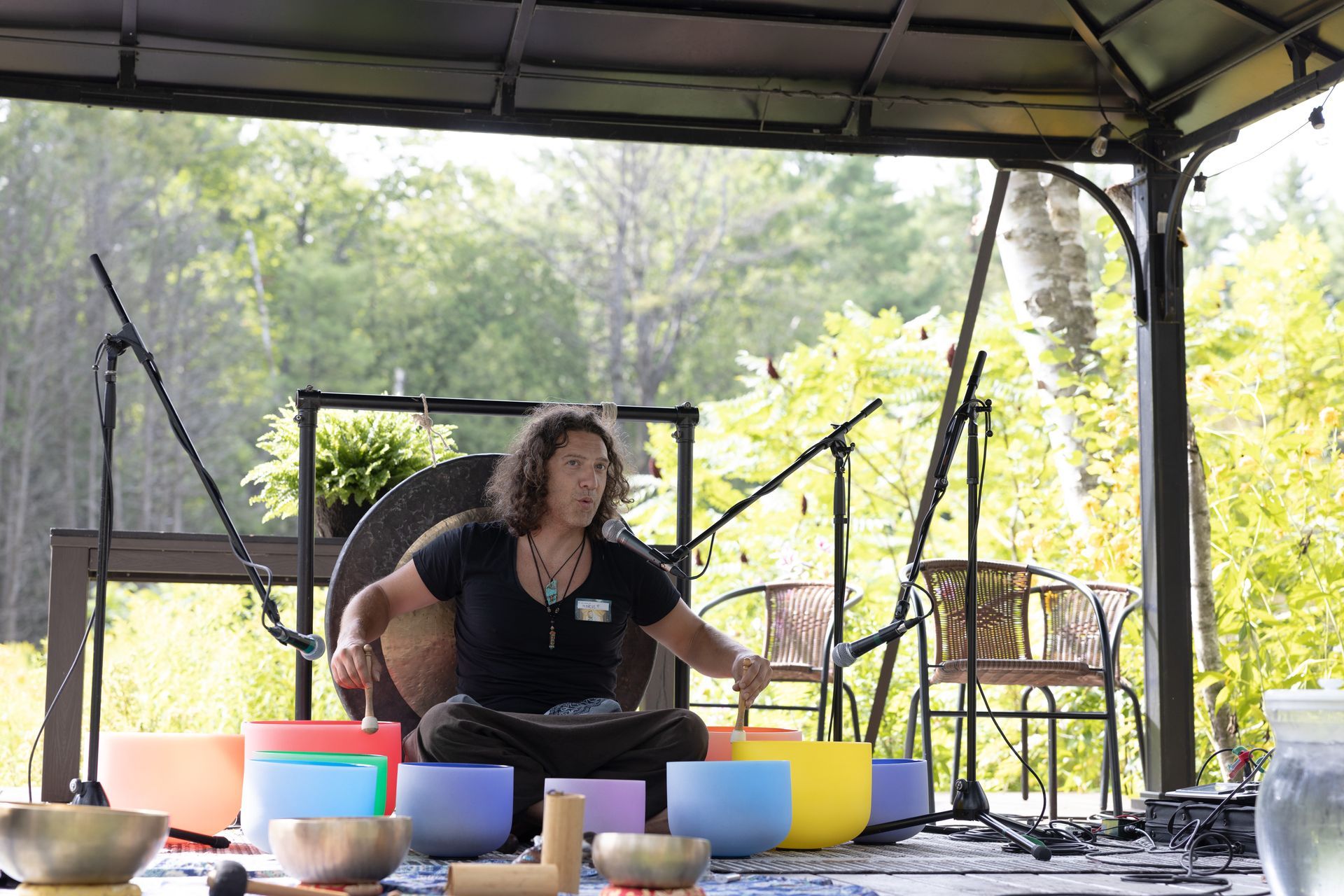 A person playing colorful singing bowls on an outdoor stage.