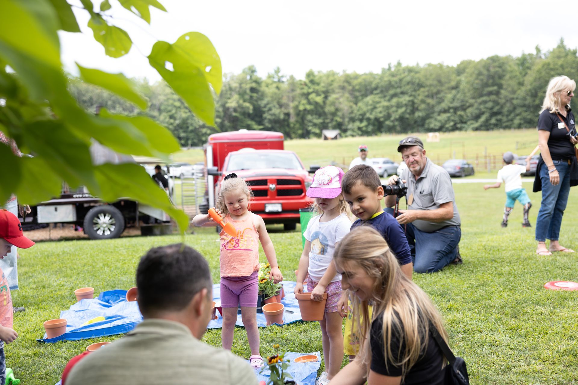 Children planting flowers outdoors with adult supervision.