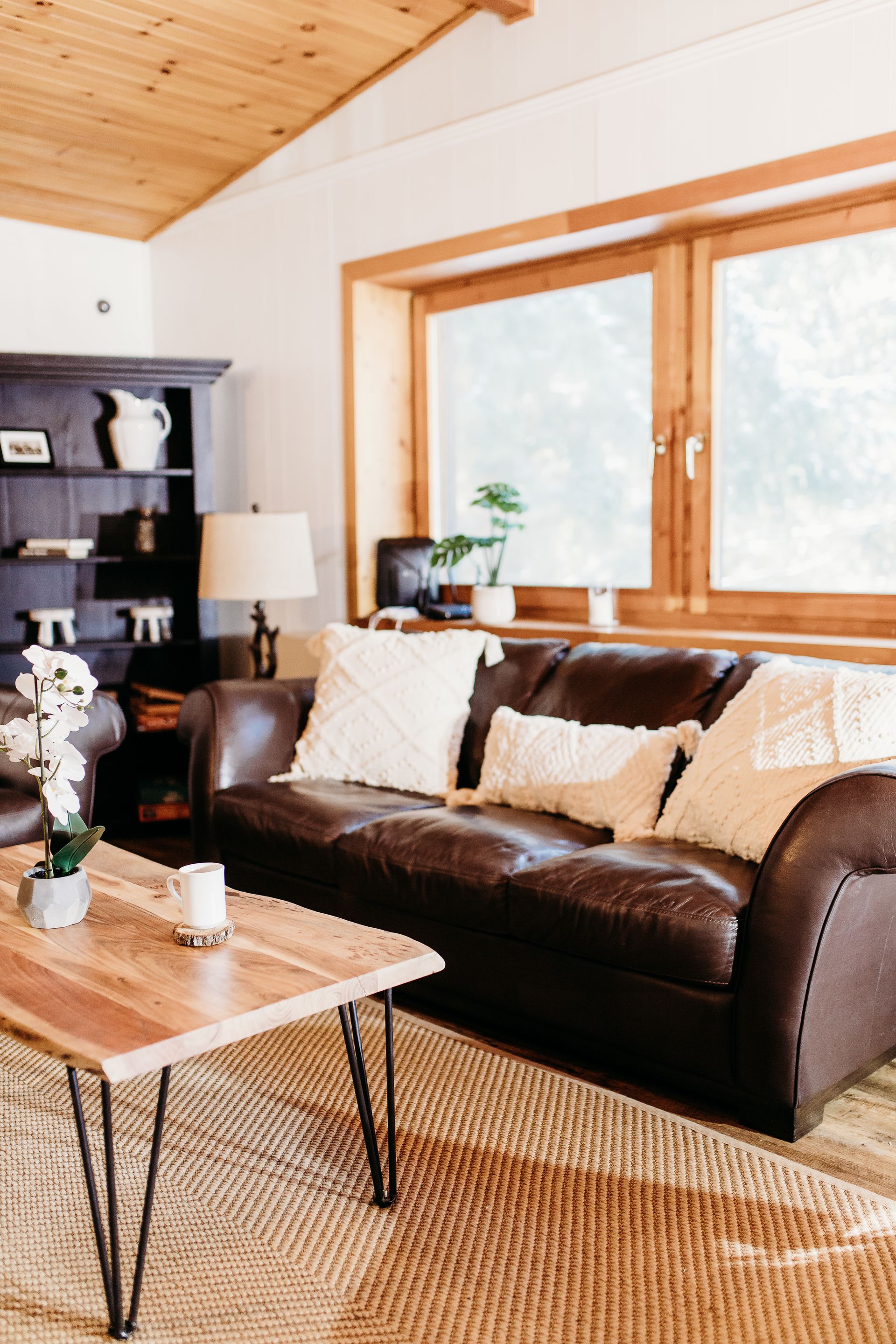 Cozy living room with brown leather sofa, wooden coffee table, and large window.