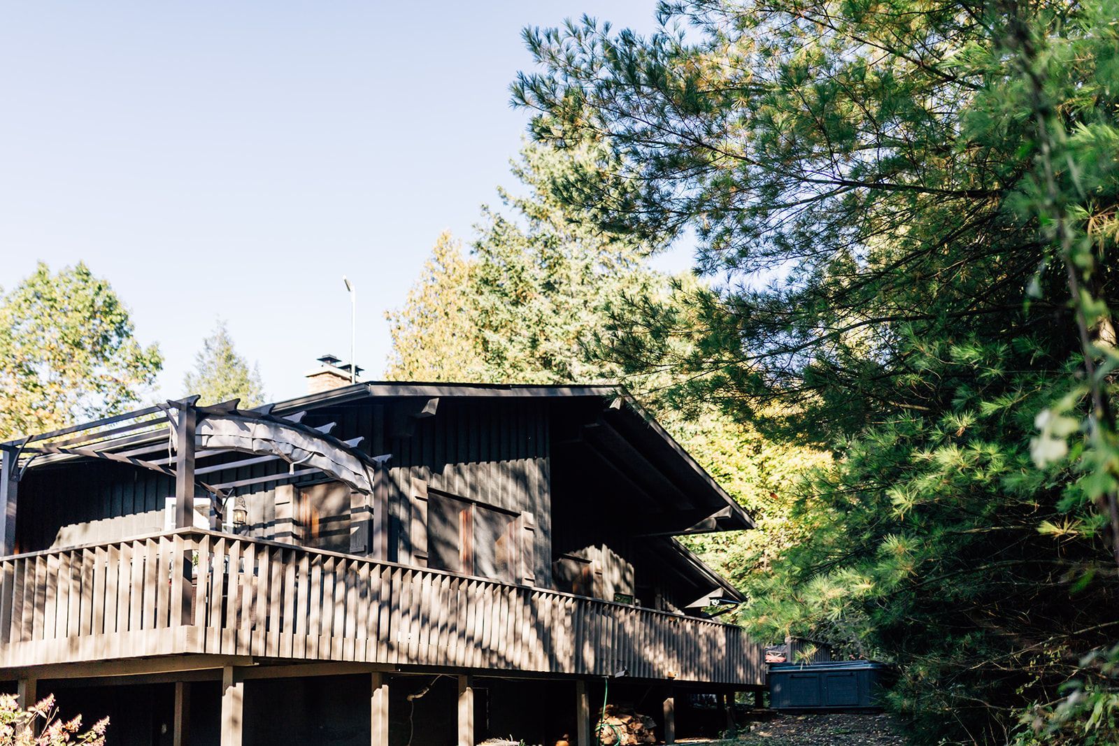 Wooden house with a porch surrounded by trees.