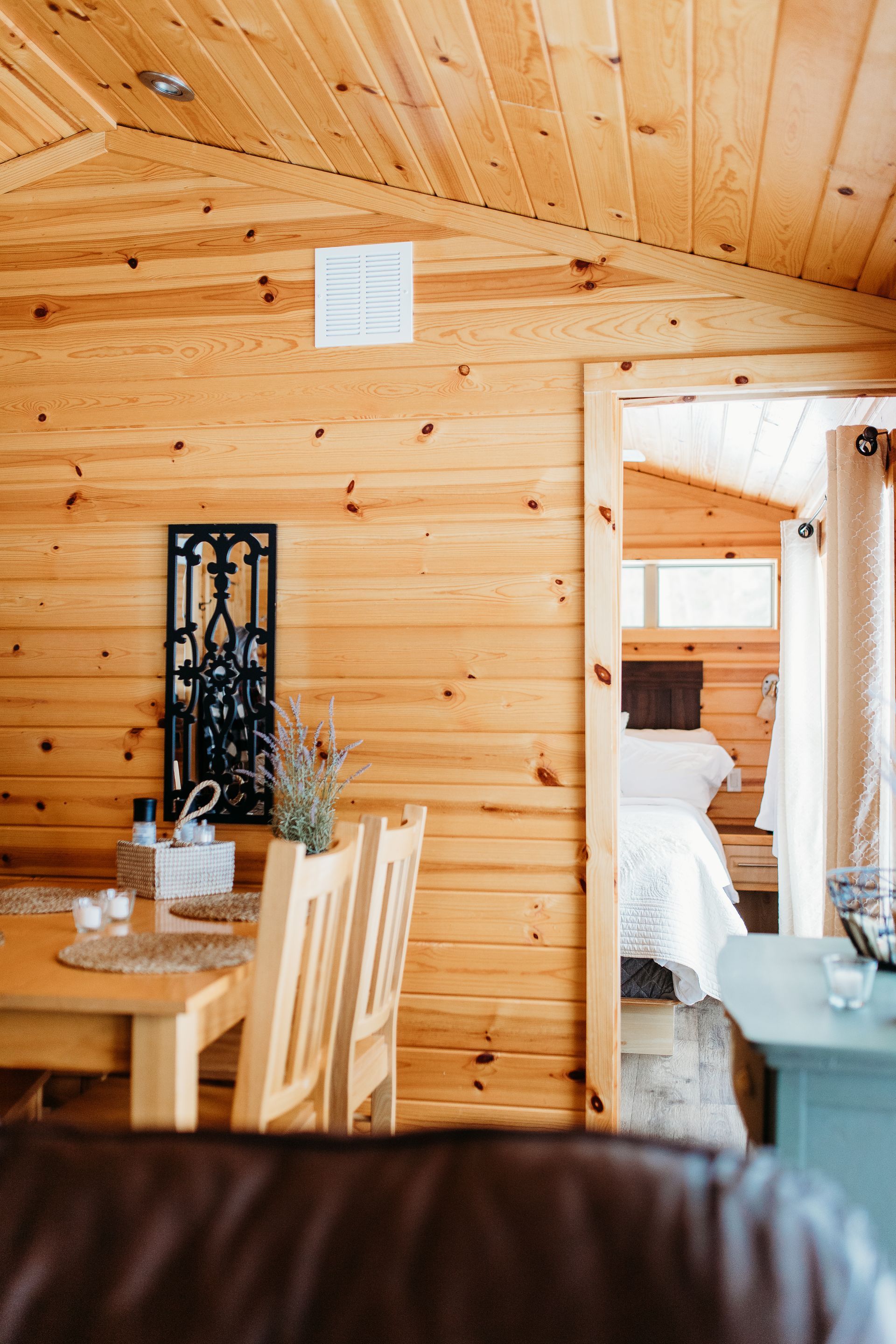 Wooden cabin interior with dining area and open doorway to a bedroom.