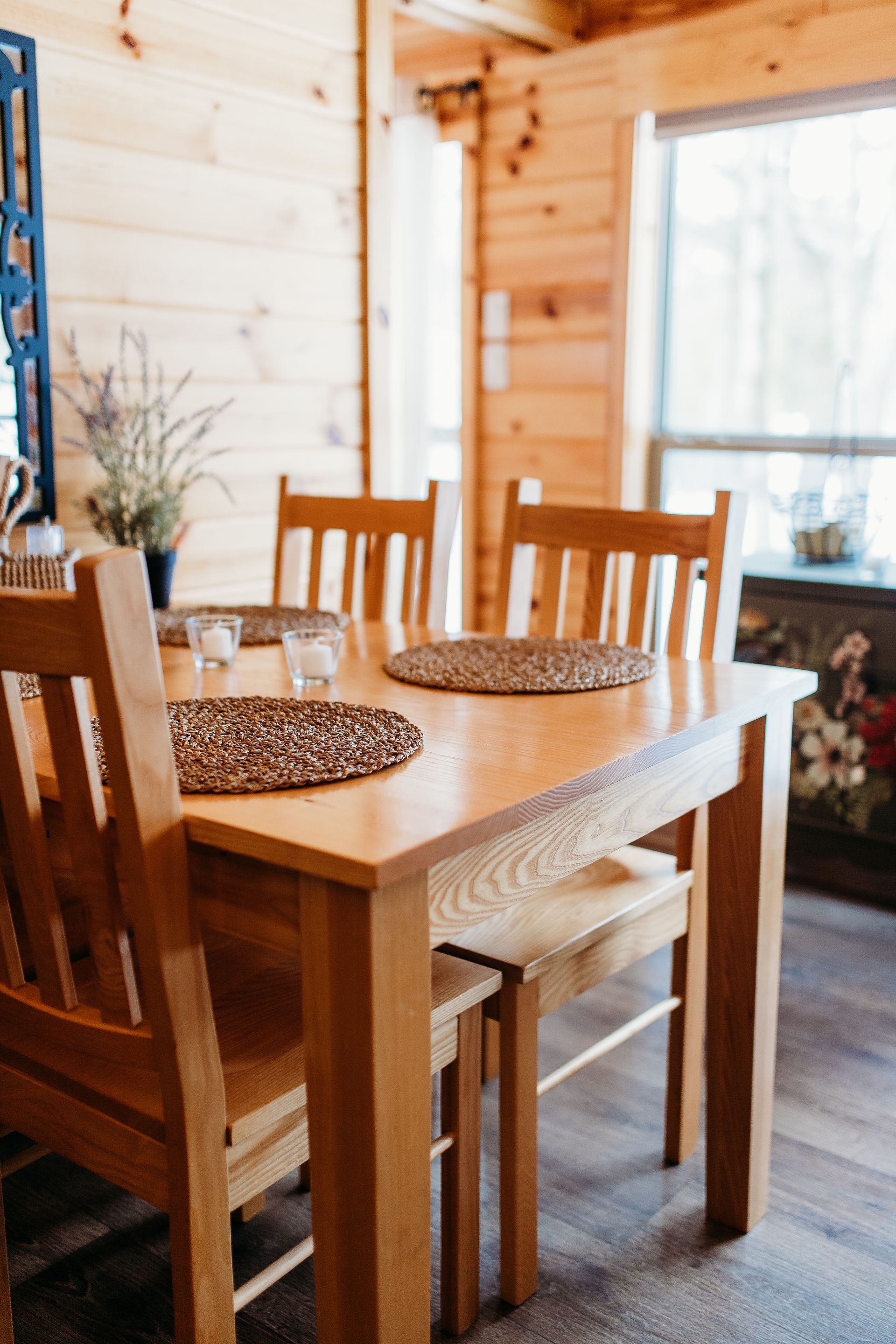 Wooden dining table with four chairs, set in a cozy, wood-paneled room.