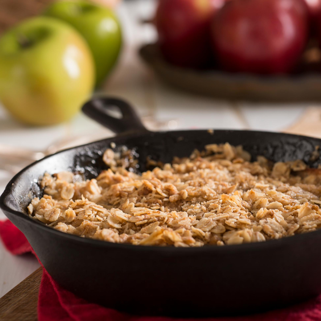 Apple crisp in a cast iron skillet with apples in the background.