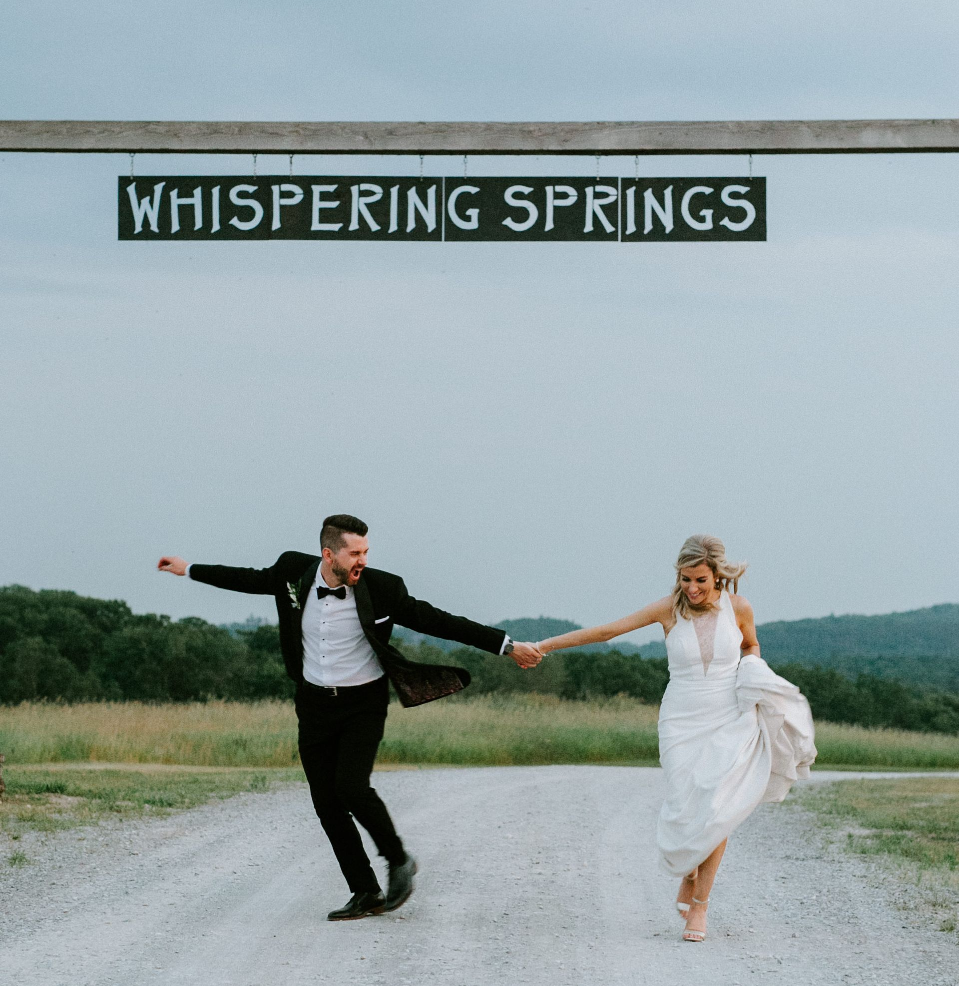 Bride and groom under the iconic Whispering Springs sign