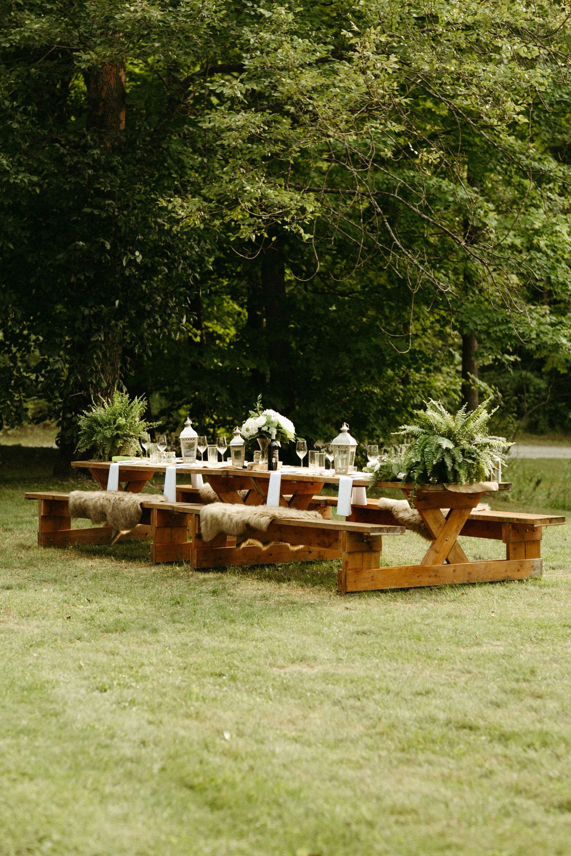 Picnic tables with decorations set in a grassy area, trees in the background.