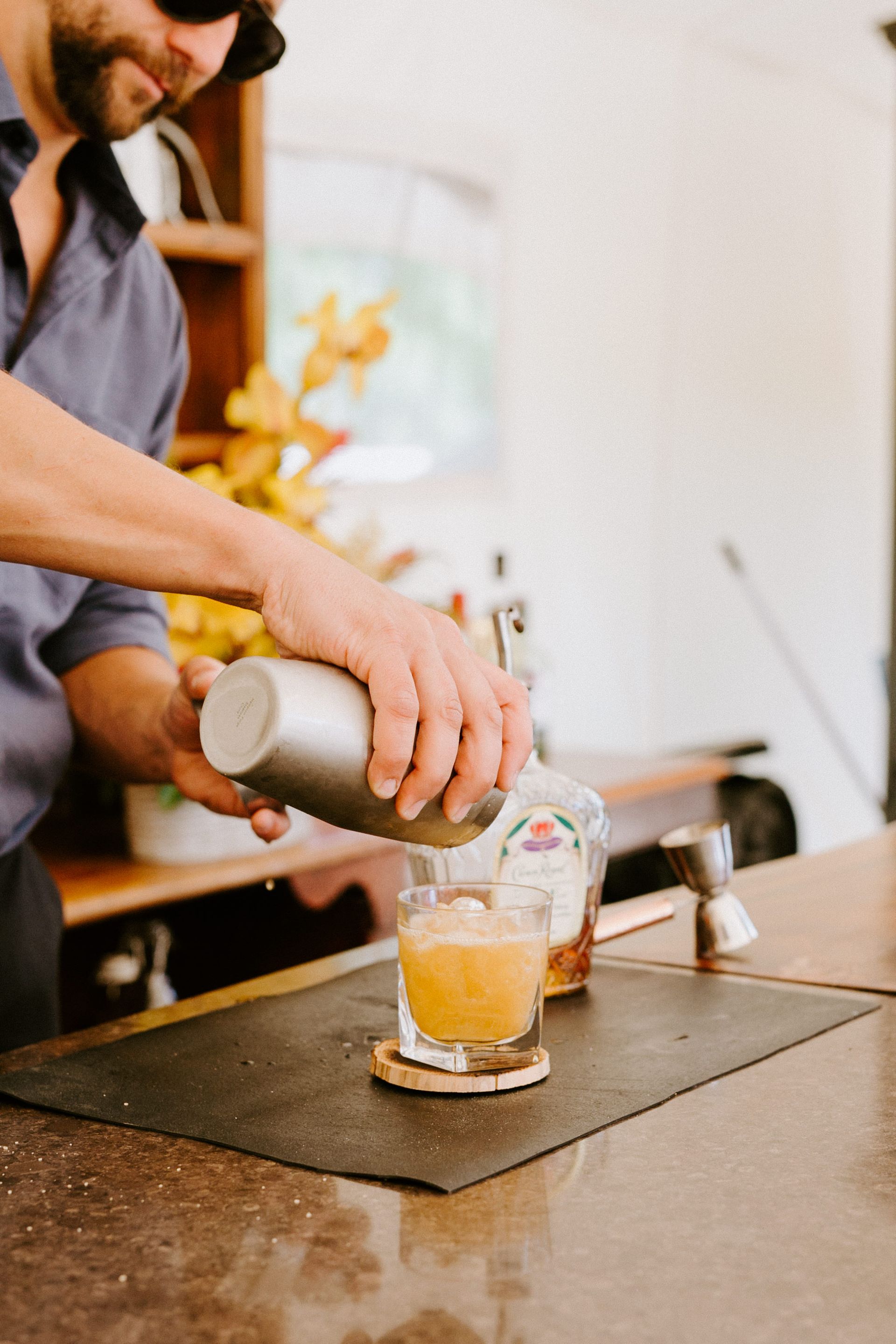 Bartender pouring cocktail from shaker into a glass with ice.