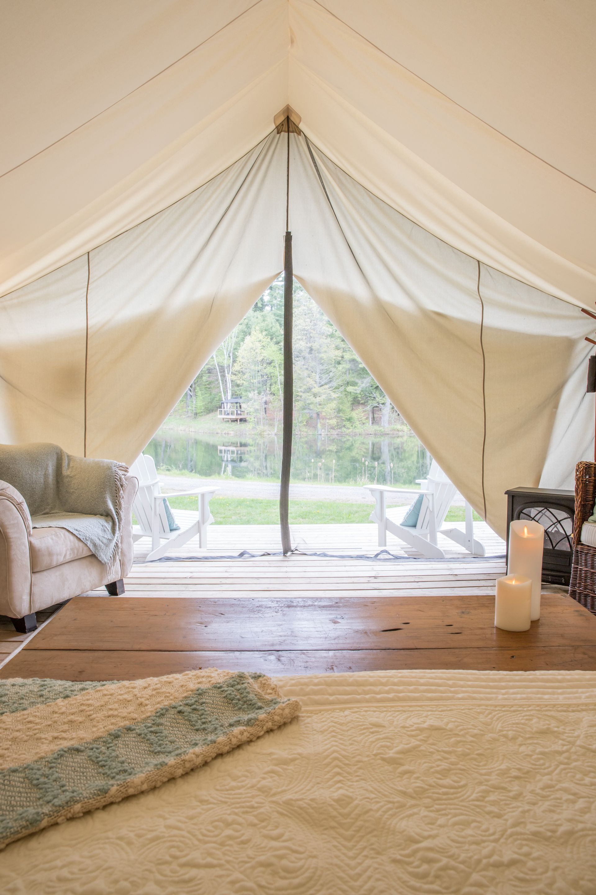 Interior of a large tent, looking outward. Light furniture, a wooden table, and a view of trees through the open front.
