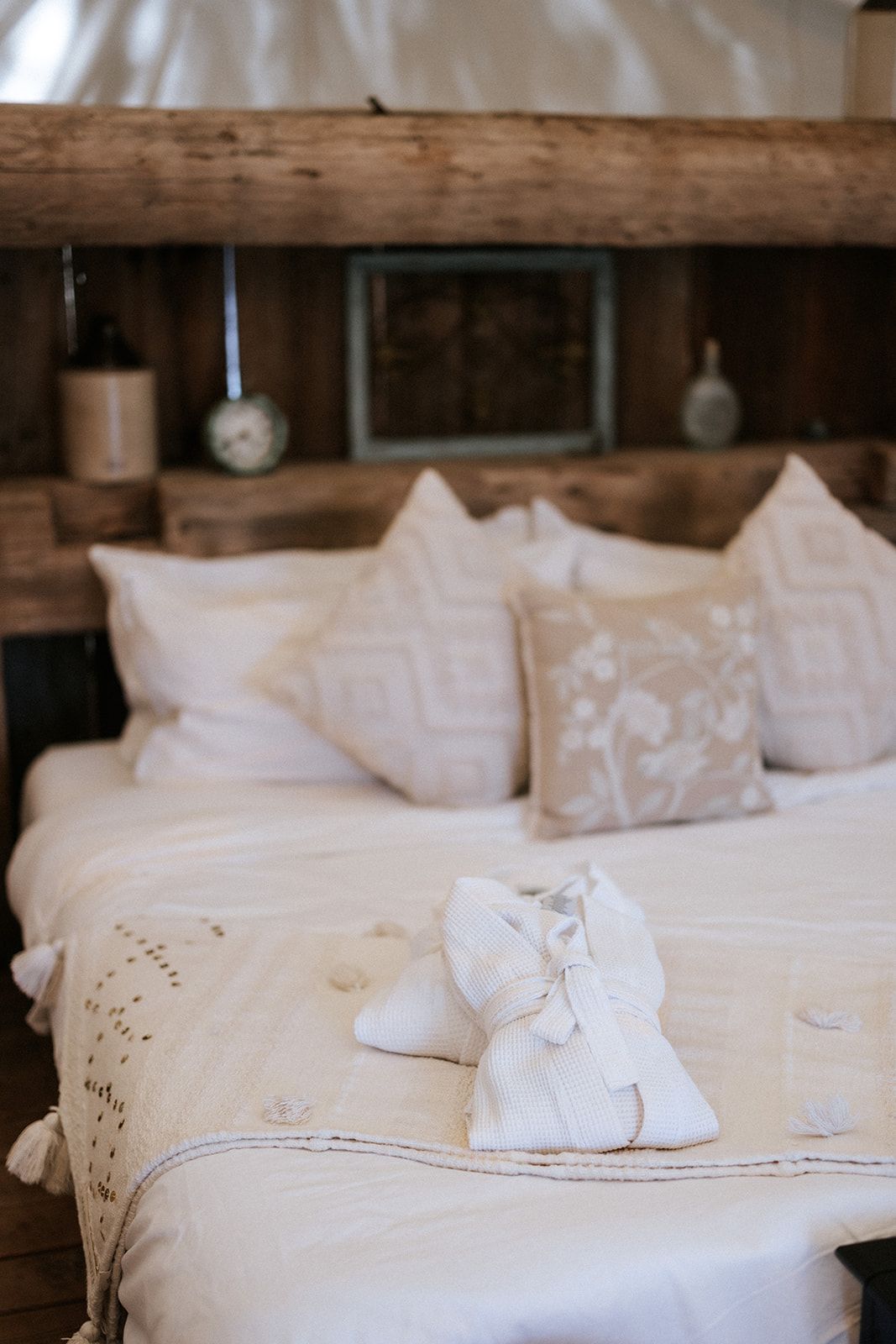 Cozy bedroom with a white bed, pillows, and folded towel in the shape of a swan. Rustic wooden headboard.