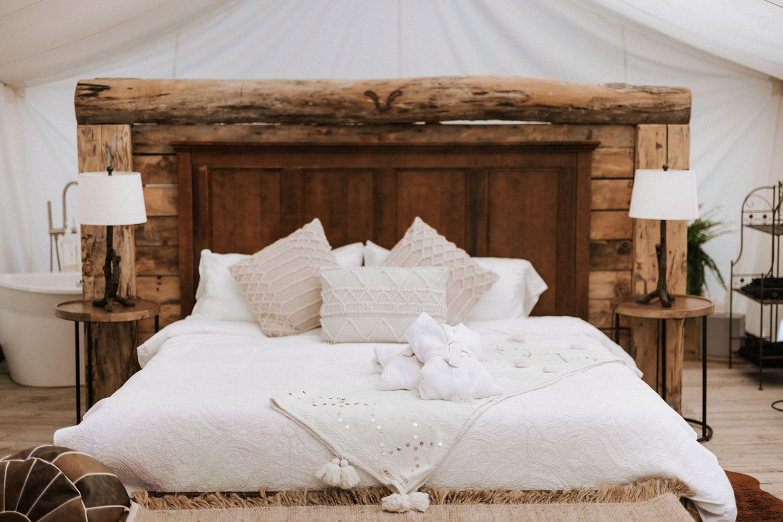 Cozy glamping bedroom with rustic wooden headboard, bed, bedside tables, and lamps.