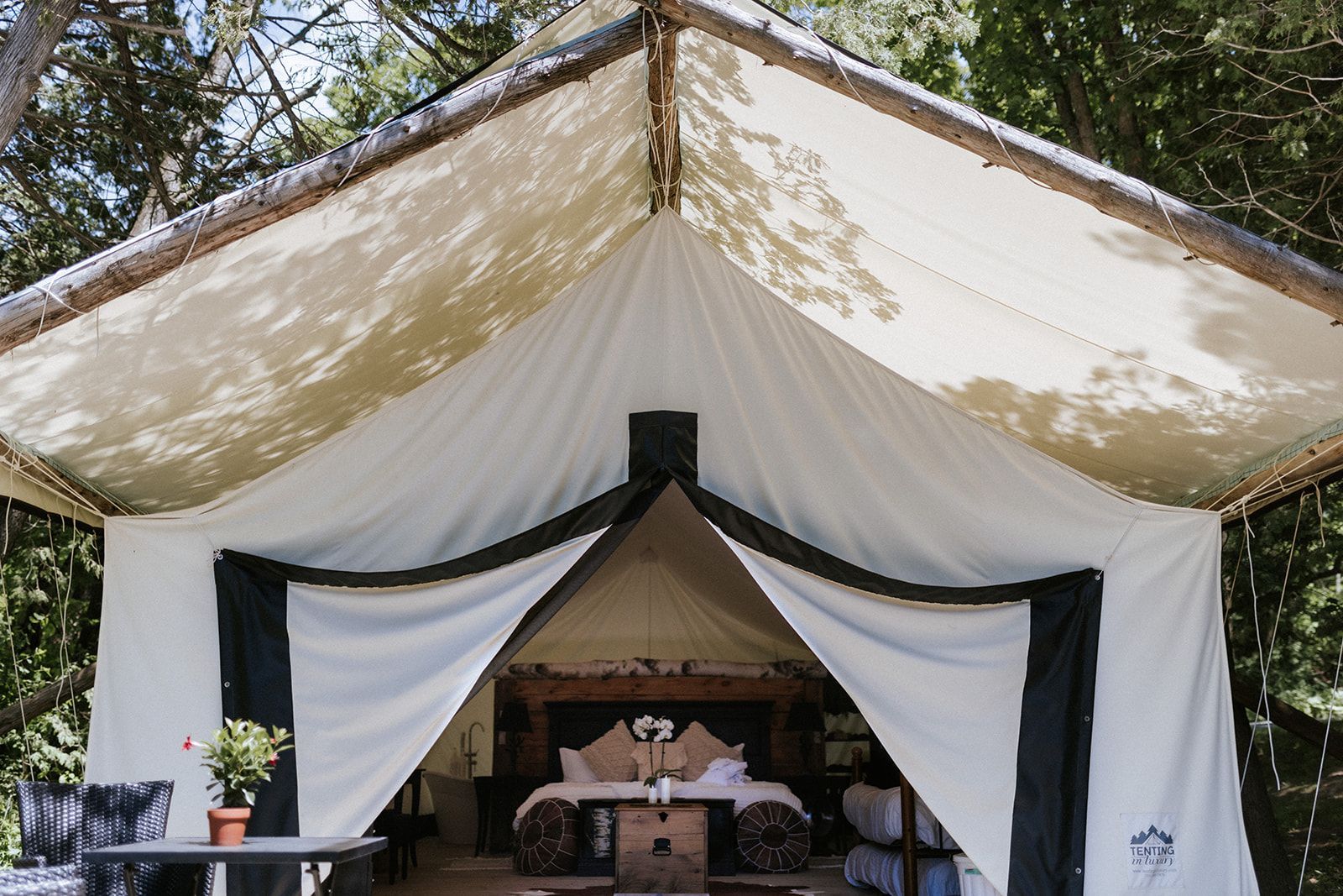 Canvas glamping tent with white and black accents; bed inside.