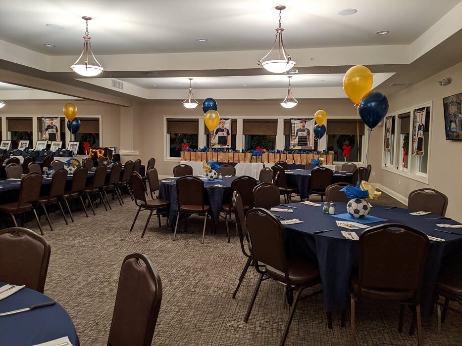 A large room filled with tables and chairs and balloons.