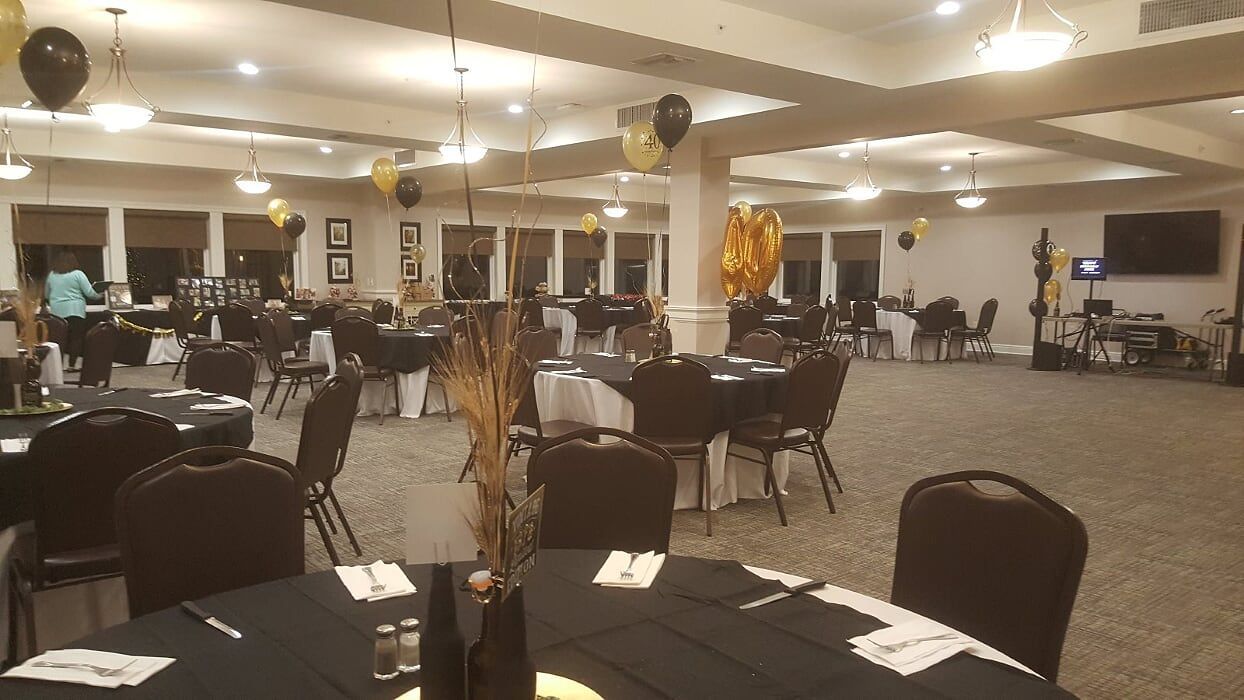A large room with tables and chairs and balloons hanging from the ceiling.
