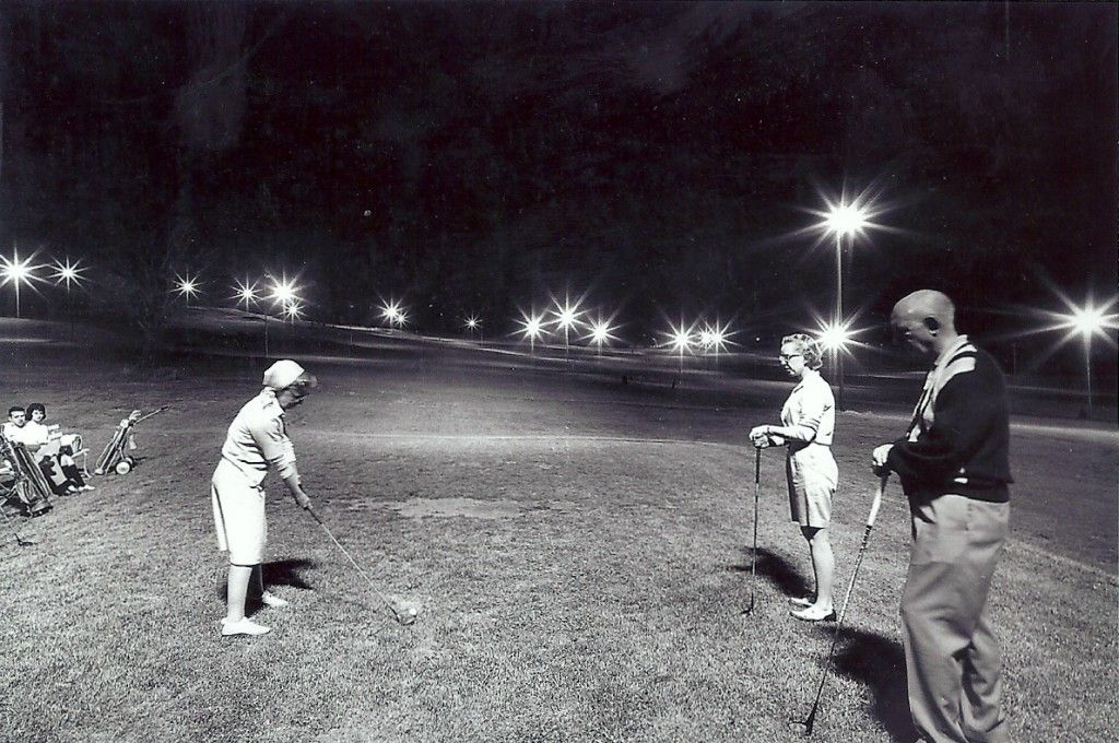 A black and white photo of people playing golf at night
