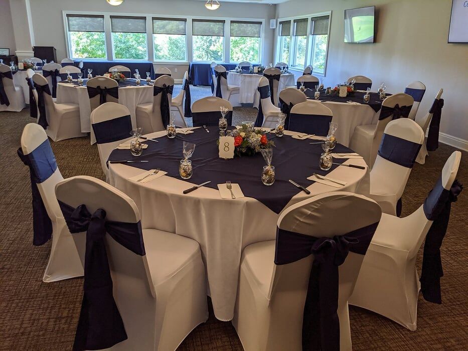 A room with tables and chairs set up for a wedding reception.