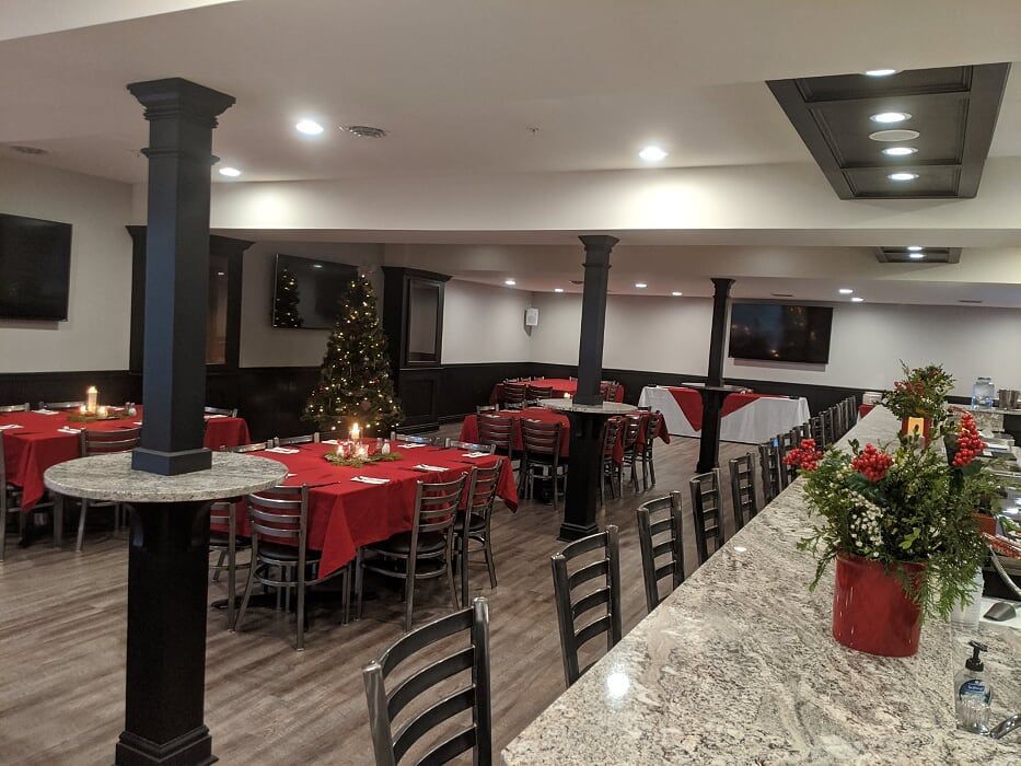 A large dining room with tables and chairs and a christmas tree.