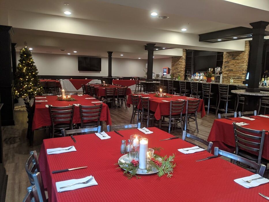 A large dining room with red tables and chairs and a christmas tree in the background.