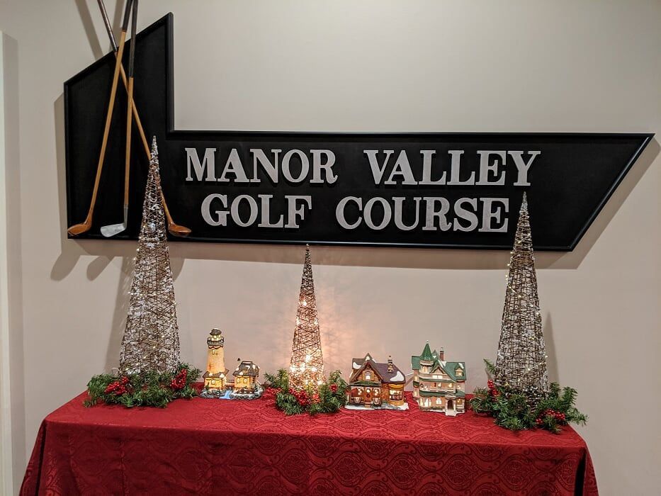 A manor valley golf course sign is above a table
