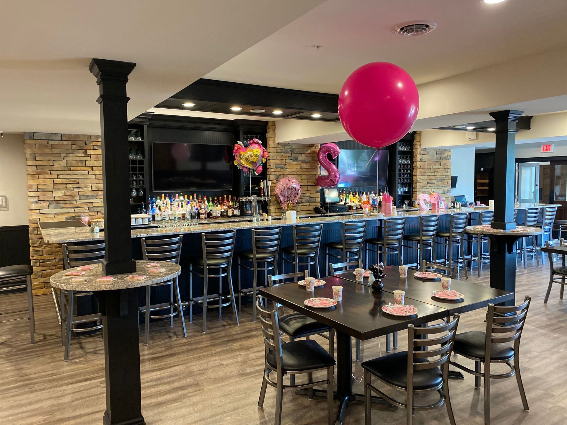 A restaurant with tables and chairs and a pink balloon hanging from the ceiling.