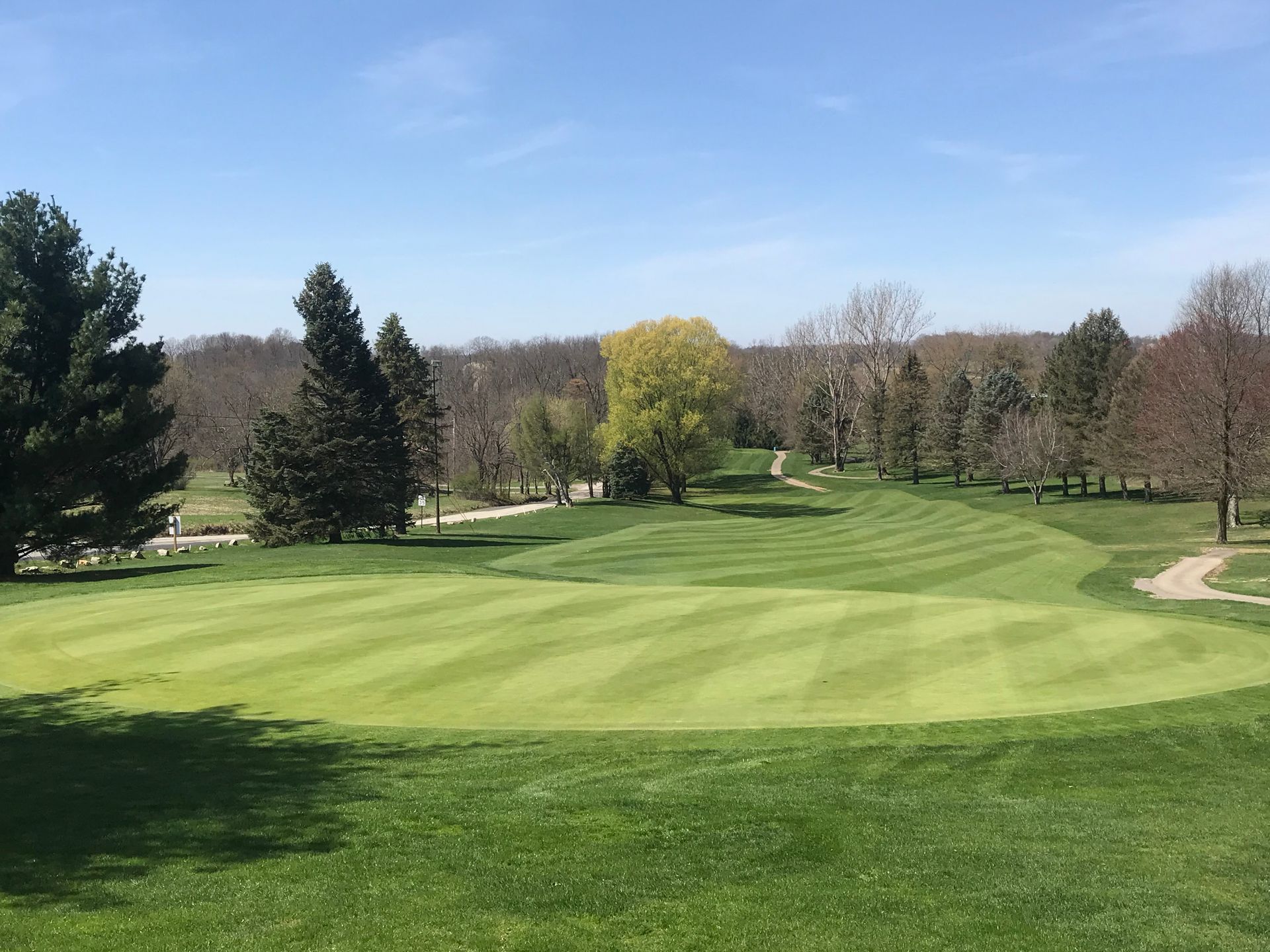 A golf course with trees and grass on a sunny day.
