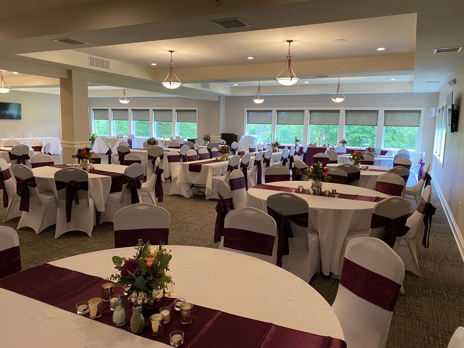 A large room with tables and chairs set up for a wedding reception.