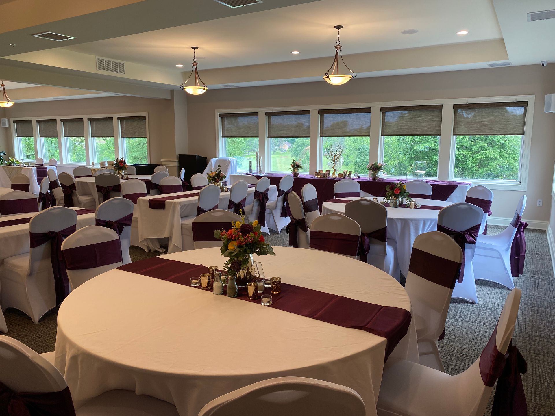 A large room with tables and chairs set up for a wedding reception.