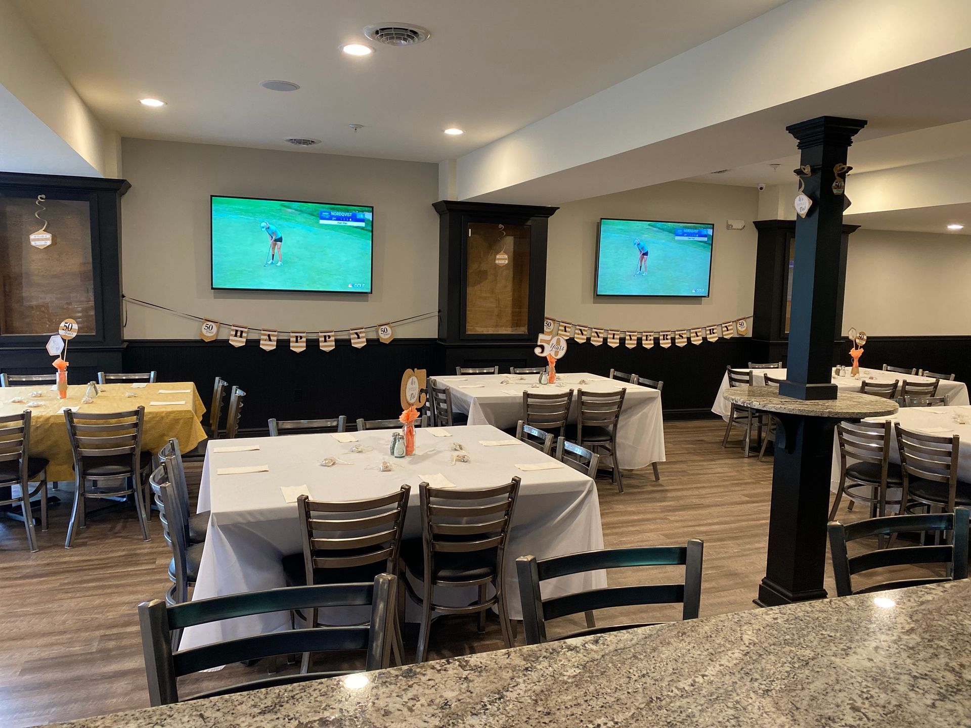 A restaurant with tables and chairs and two televisions on the wall.
