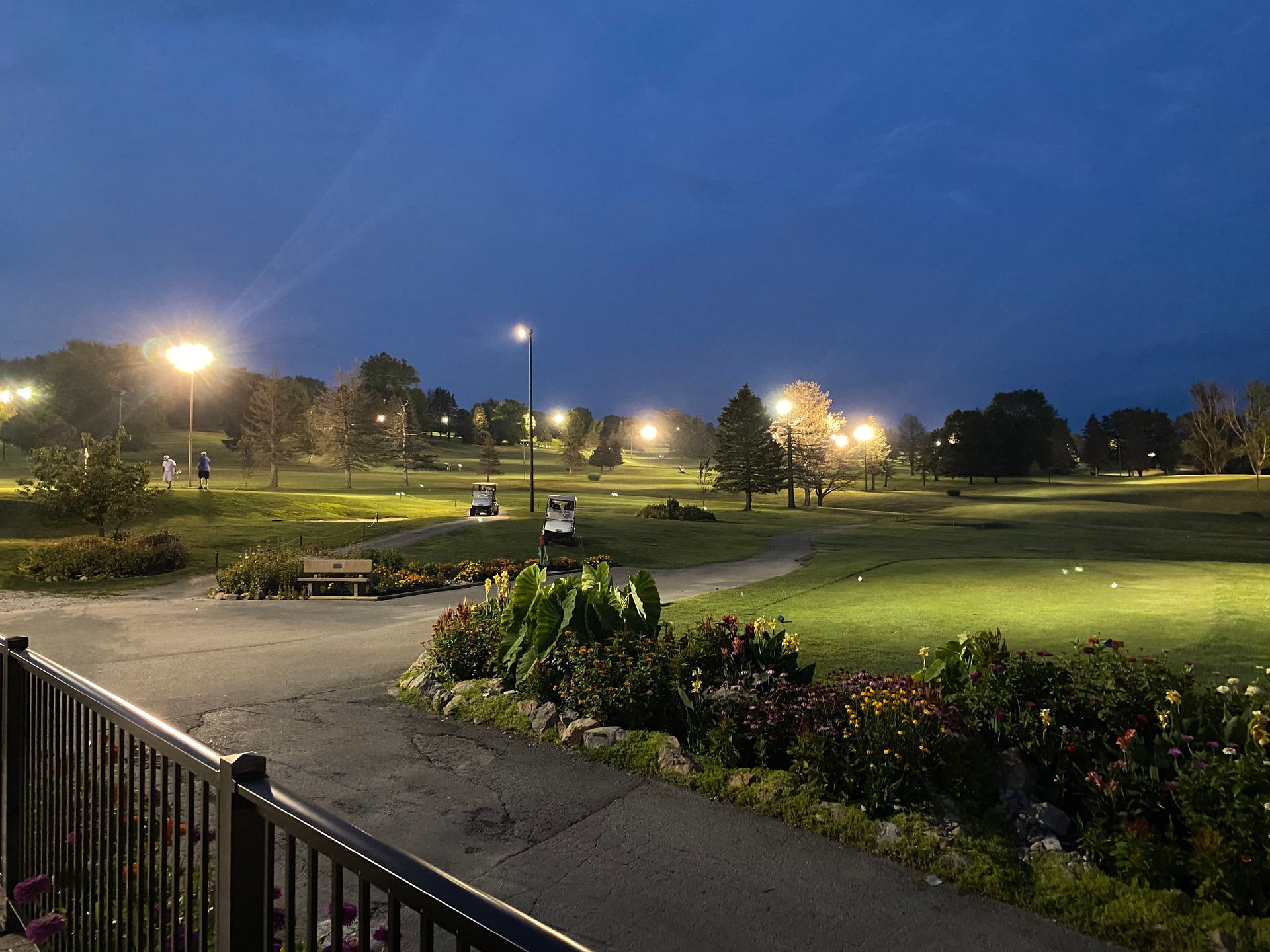 A view of a golf course at night with a fence in the foreground.