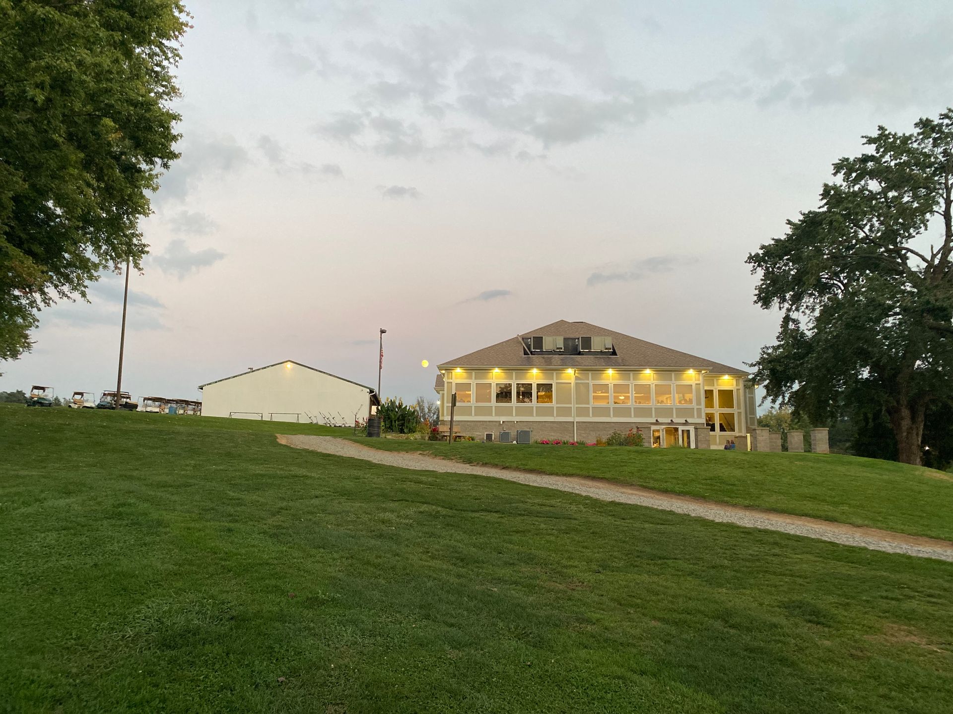 A large white house is sitting on top of a grassy hill.
